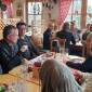 Der Landesbischof sitzt mit mehreren Personen beim Essen.